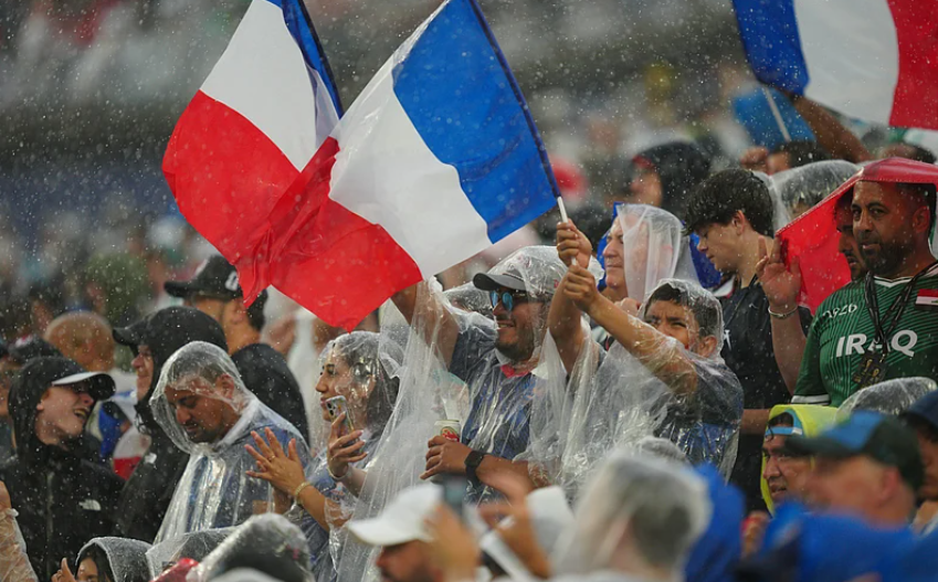 France fans wave French flags in rain during World Cup match against Iraq