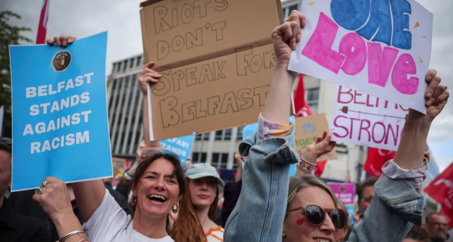 Protesters gather in Belfast city centre holding signs reading “Belfast Stands Against Racism,” “Riots Don