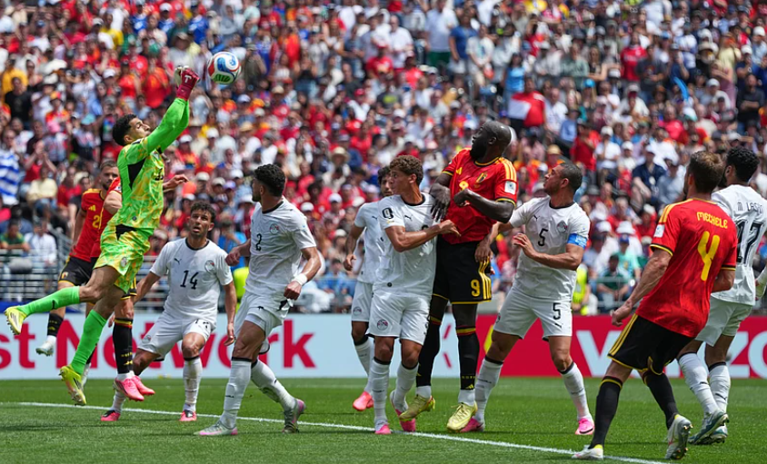 Egypt goalkeeper Mostafa Shoubir punches the ball clear under pressure from Belgium attackers