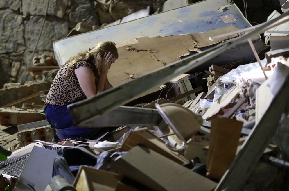 A woman sits beside the rubble of a collapsed building after the devastating Venezuela earthquake, overwhelmed with grief as rescue operations continue.