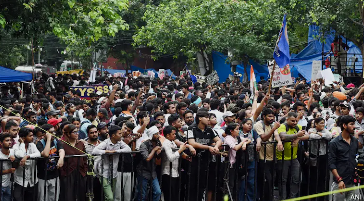 Large crowd of young protesters gathered behind barricades demanding accountability over alleged examination irregularities