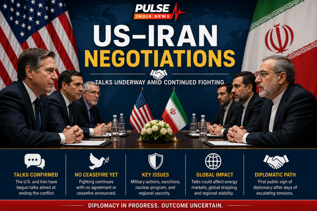 US and Iranian representatives seated across a negotiation table beneath the US and Iran flags, with a headline stating that talks are underway amid continued fighting.