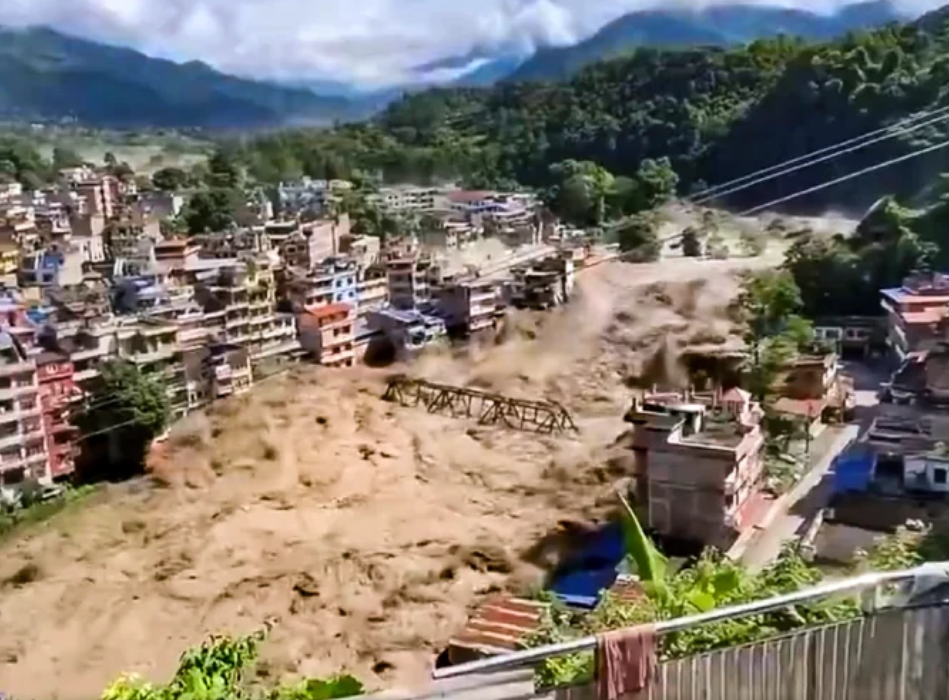 Massive muddy floodwaters sweeping through buildings in a Nepalese town