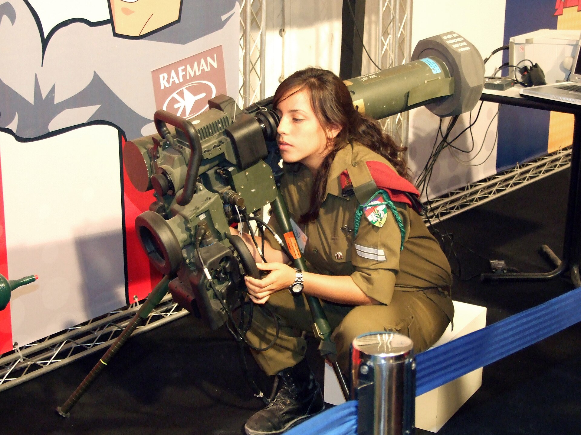 Israeli soldier examining the sighting unit of a tripod-mounted Spike anti-tank guided missile launcher at an exhibition