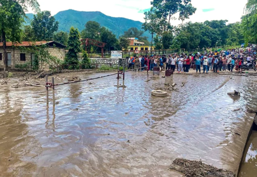 Flood-affected residents gather beside a waterlogged road after homes were damaged in Nepal