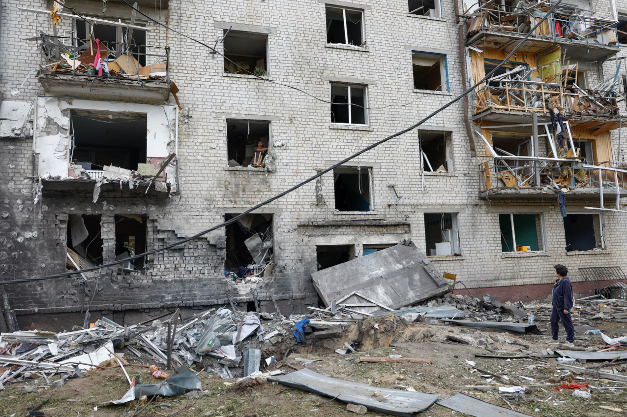 A woman stands amid debris outside a heavily damaged apartment building following a Russian missile strike in Boryspil
