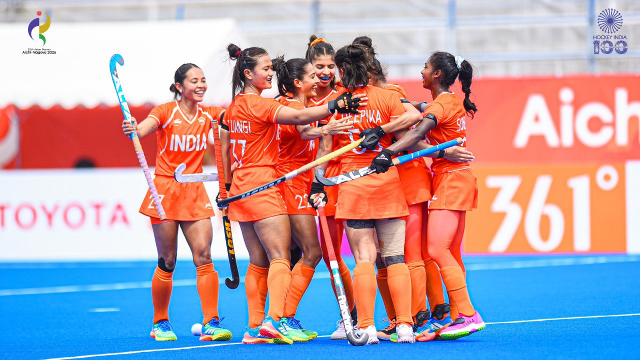 Indian women's hockey players celebrate together on the field