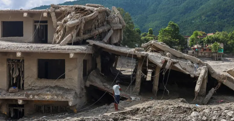 A man stands near a severely damaged building covered in mud and debris after the Nepal floods