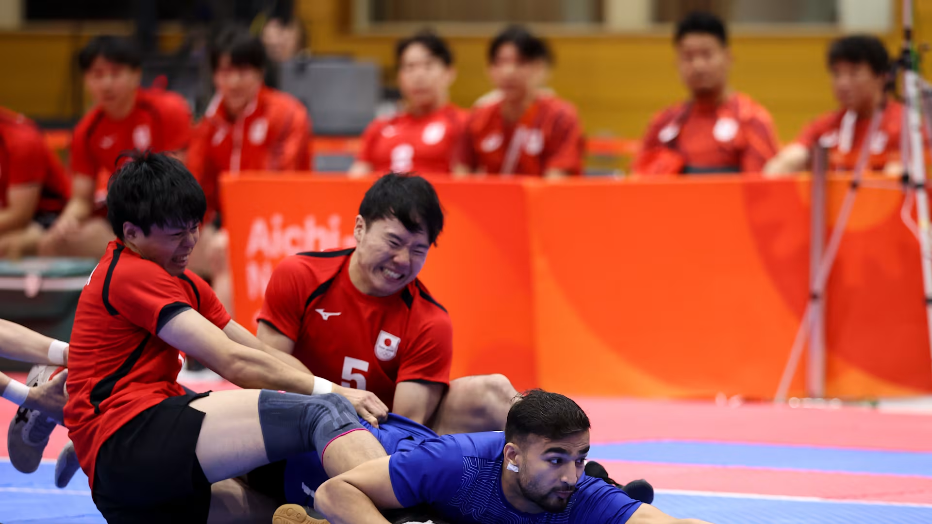 Two Japanese kabaddi defenders tackle an Indian raider during the men's Asian Games 2026 group match