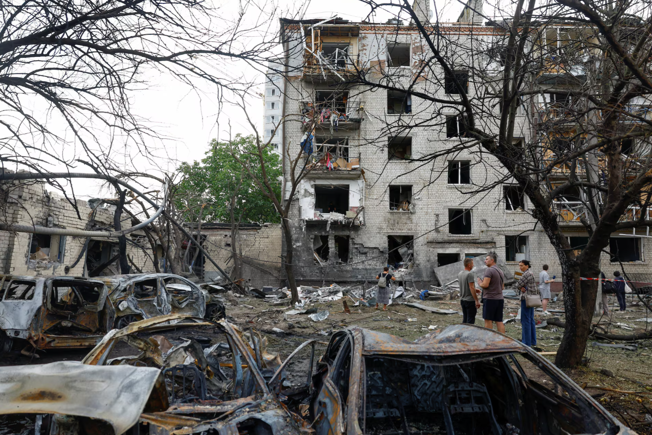 Residents stand outside a missile-damaged apartment building surrounded by burned vehicles and debris in Boryspil, Ukraine
