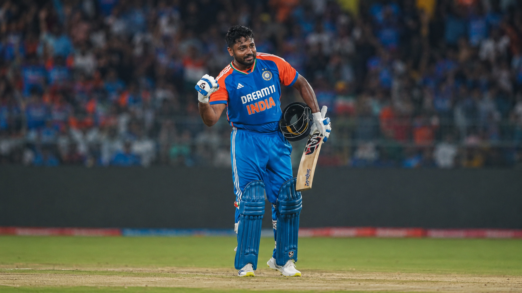 Sanju Samson celebrates while holding his cricket bat and helmet in India colours