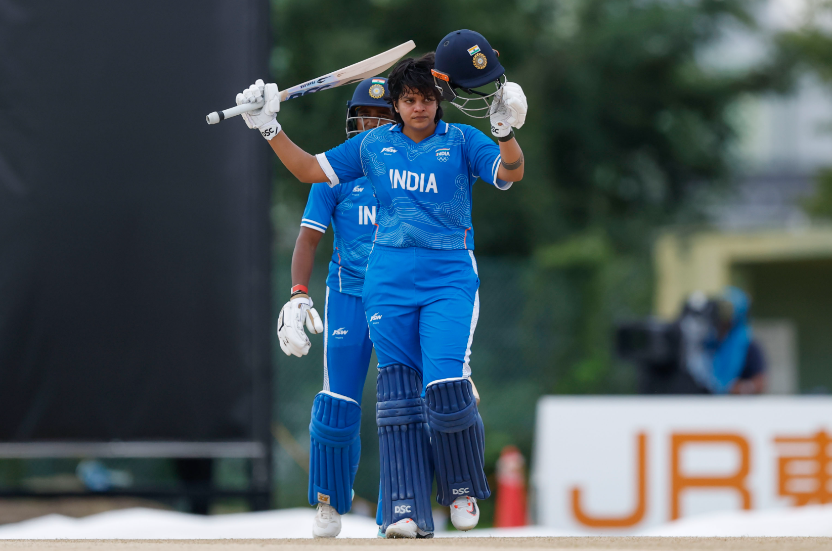Shafali Verma raises her bat and helmet after scoring a century against Bangladesh at the Asian Games 2026