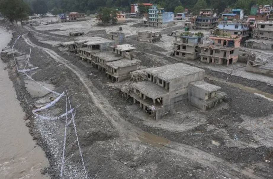 Aerial view of mud and debris surrounding buildings beside a river in Devighat, Nuwakot, Nepal